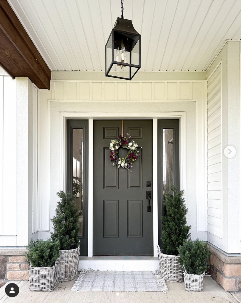 A Black Door Framed by Two Grey Wicker Planters