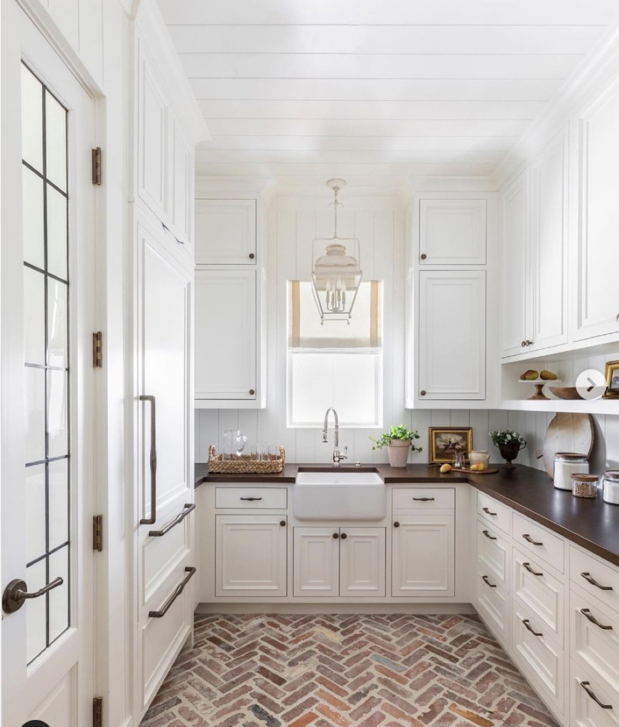 A Kitchen with Off-White Cabinets and Brick Flooring