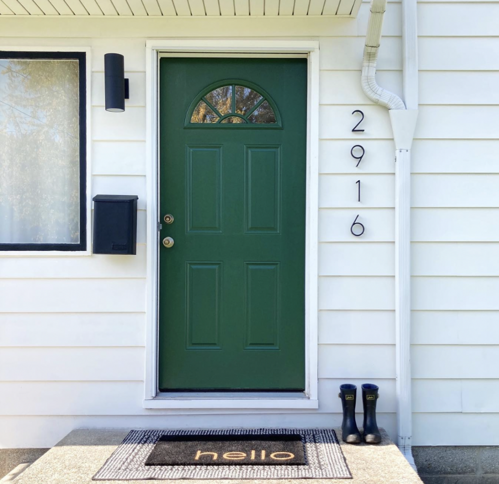 A minimalist front door in dark green on a white house