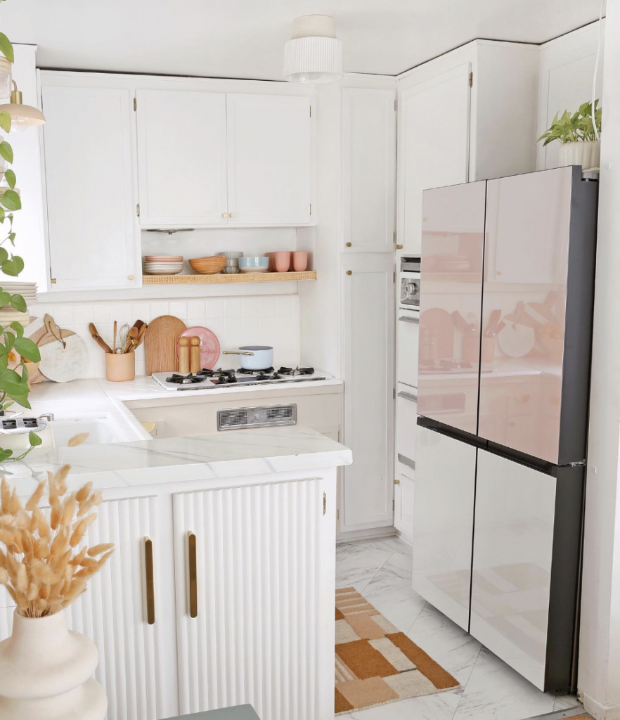 A small white kitchen beside a white stainless steel refrigerator