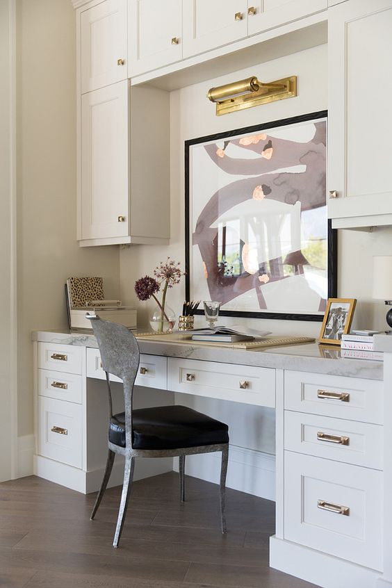 A White Built-In Desk with an Art Display and Marble Countertop