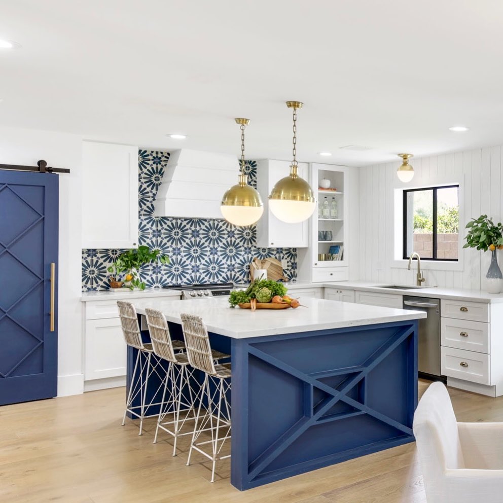 Bohemian kitchen with navy island, vibrant backsplash, and woven stools