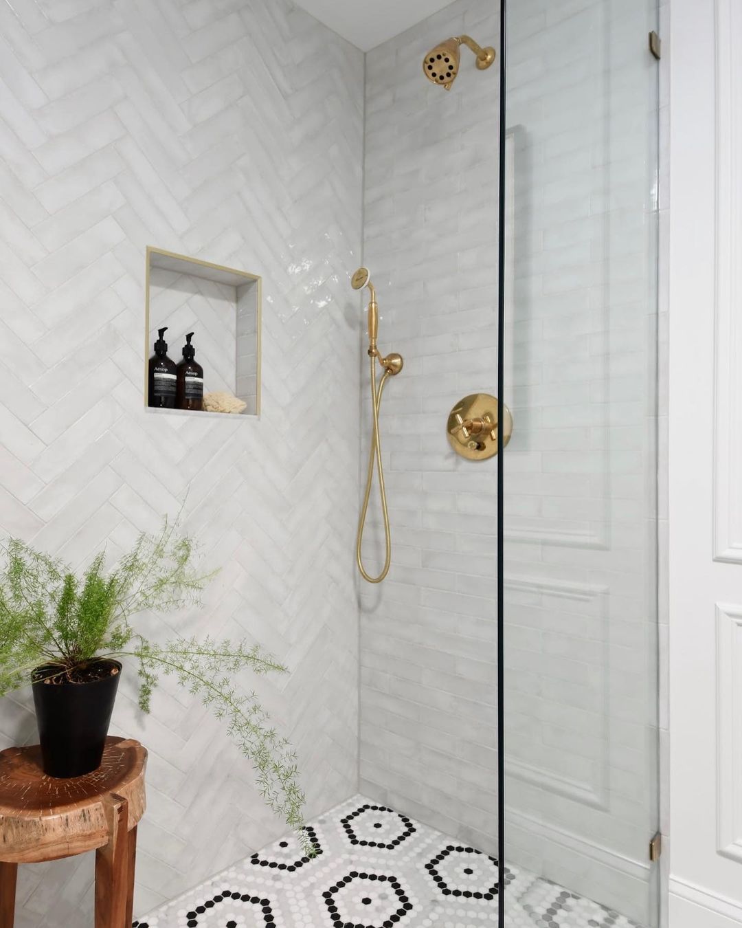 Chic Herringbone Tile Shower with Gold Fixtures and Patterned Floor