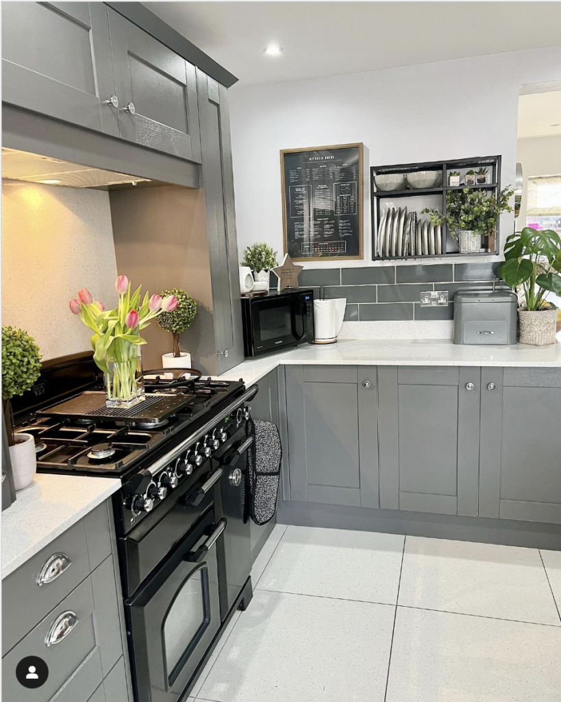Cool Muted Dark Gray Cabinets with Silver Hardware Balancing Warm Wood and Stone Countertops with Cool Stainless Steel Appliances