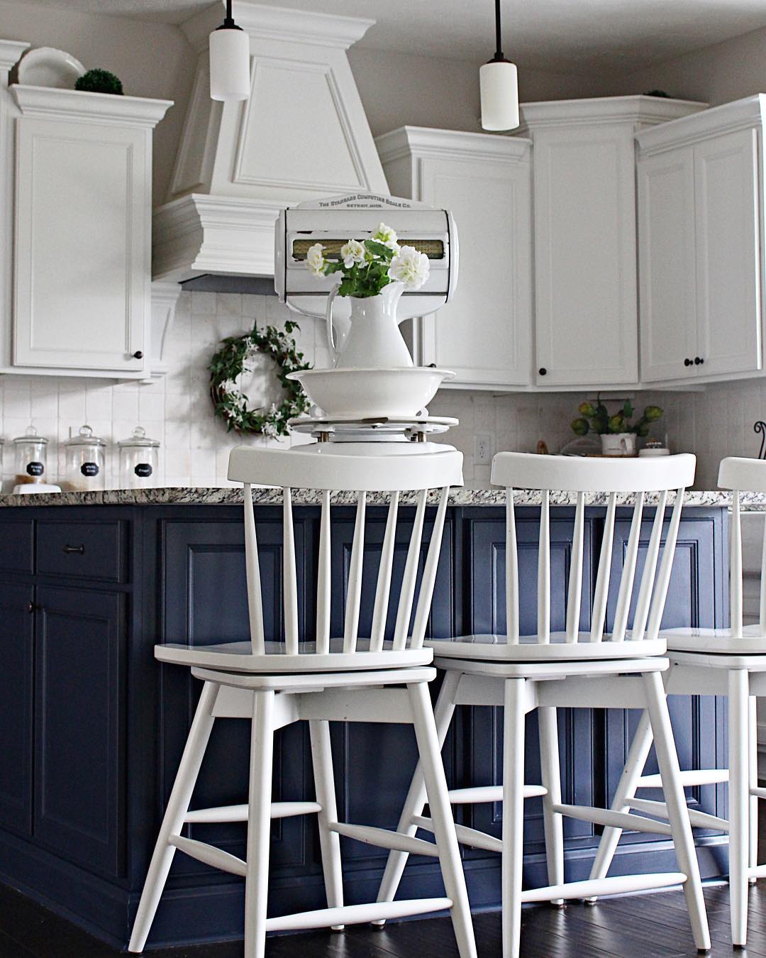 Navy island with white spindle-back chairs and dark wood floors