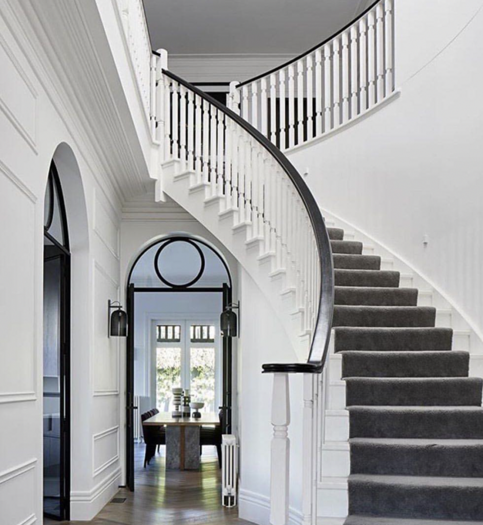 Curved staircase featuring white steps and a grey carpet runner