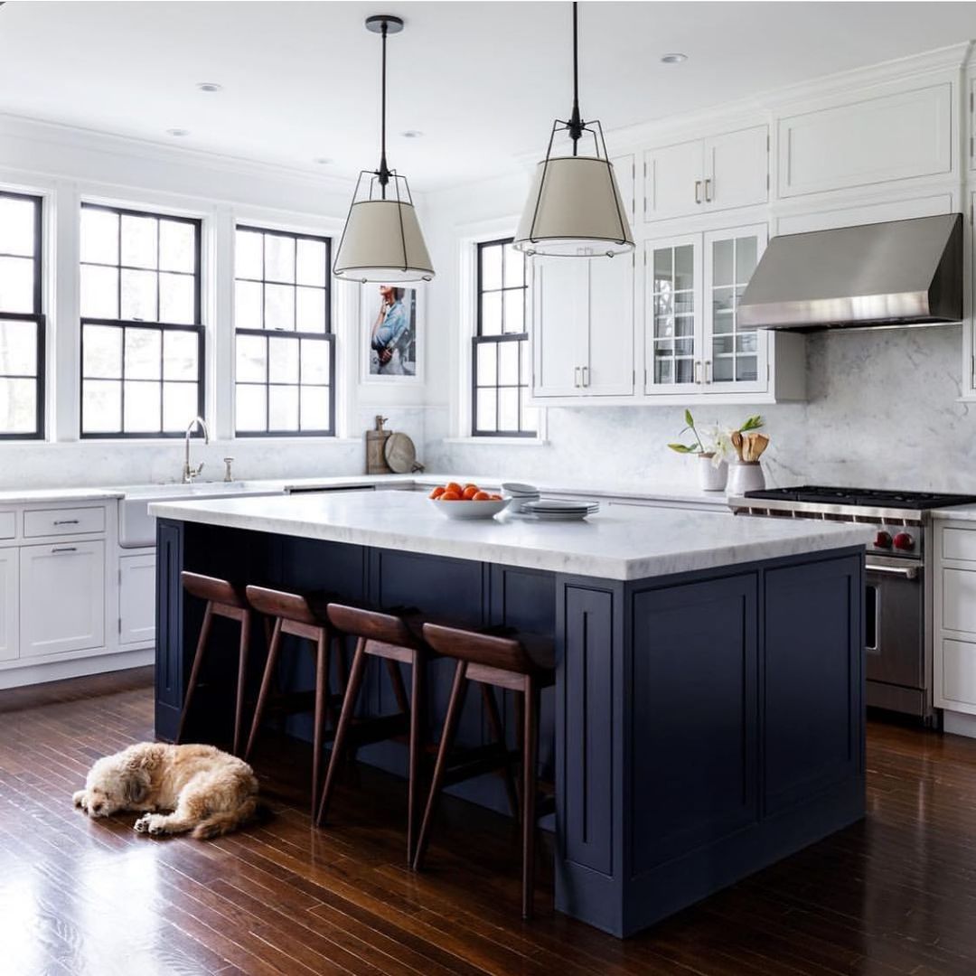 Navy island with beige pendants and warm wooden floor in family kitchen