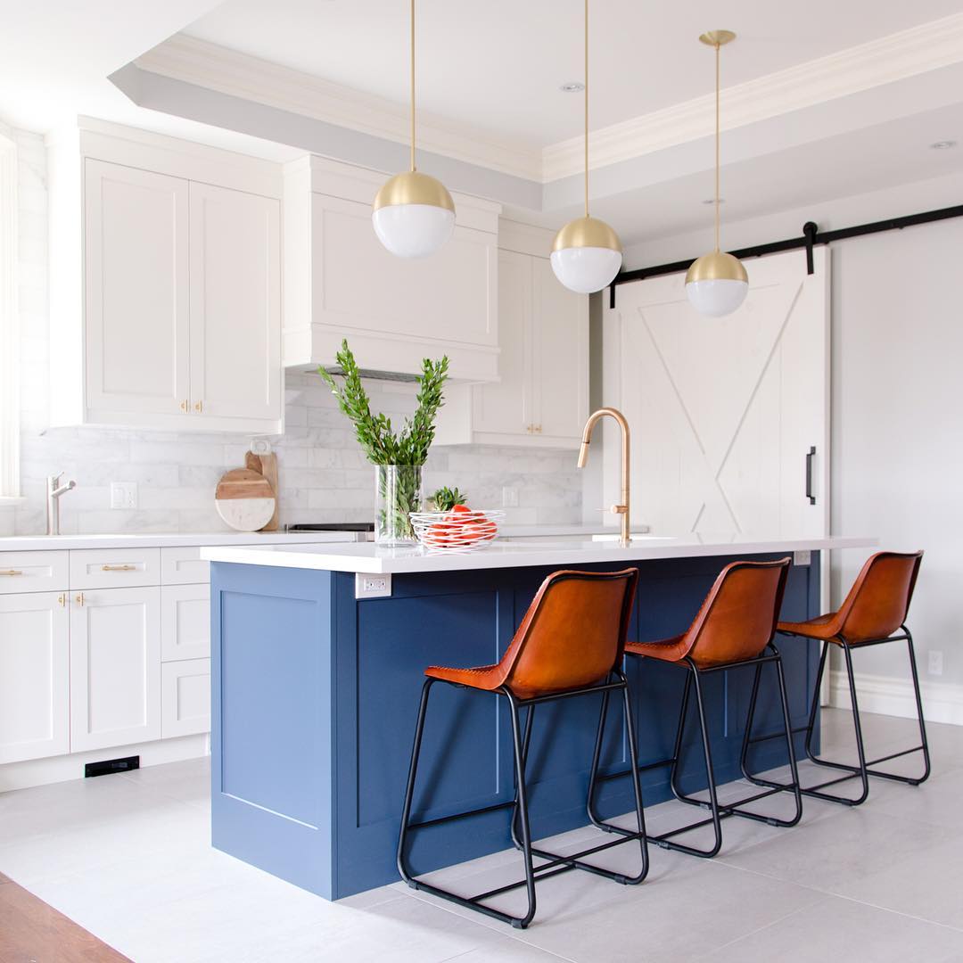 Navy island with tan leather stools and gold pendant lights