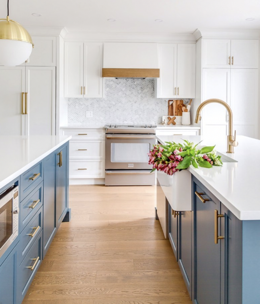 Modern Island in a Blue Kitchen With White Countertops and Gold Faucet