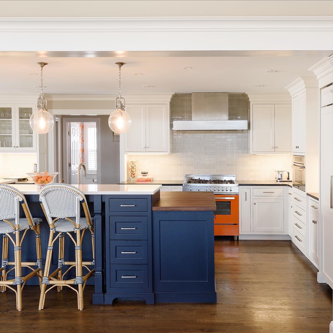 Navy island with bistro chairs, wooden countertop, and industrial pendant lights