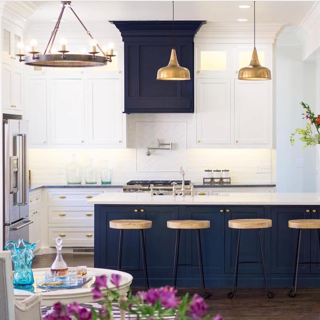Navy kitchen island with brass hardware, pendant lights, and marble backsplash