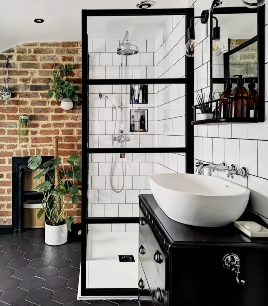 Red brick accent wall with rough texture and earthy tones for rustic character, paired with a black vanity top and white bathroom elements in a black-and-white palette for modern style and contemporary look