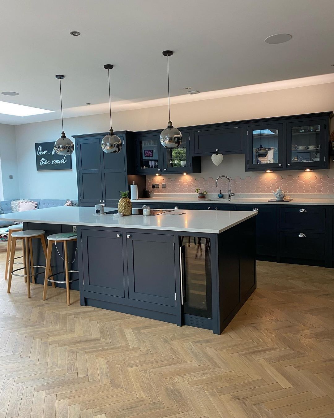 Navy island with hexagonal backsplash, herringbone floor, and open shelving