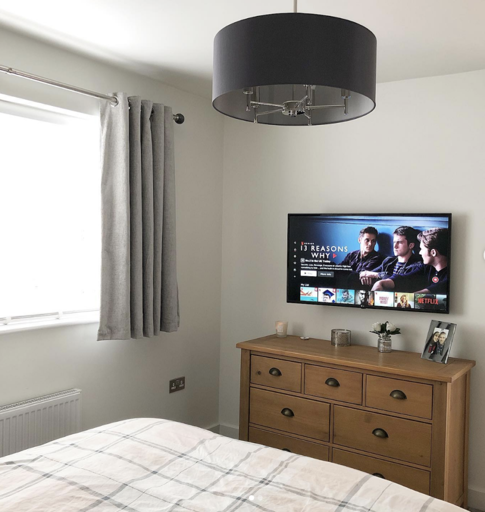 Small Minimalist Bedroom TVs Above a Wooden Dresser