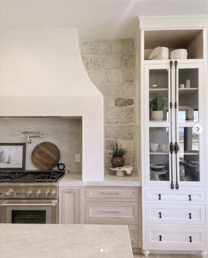 White and wood cabinets in a two-tone kitchen with stone wall