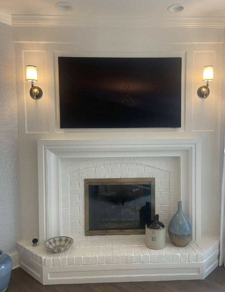 White Fireplace TV Above with Sconces and Bench