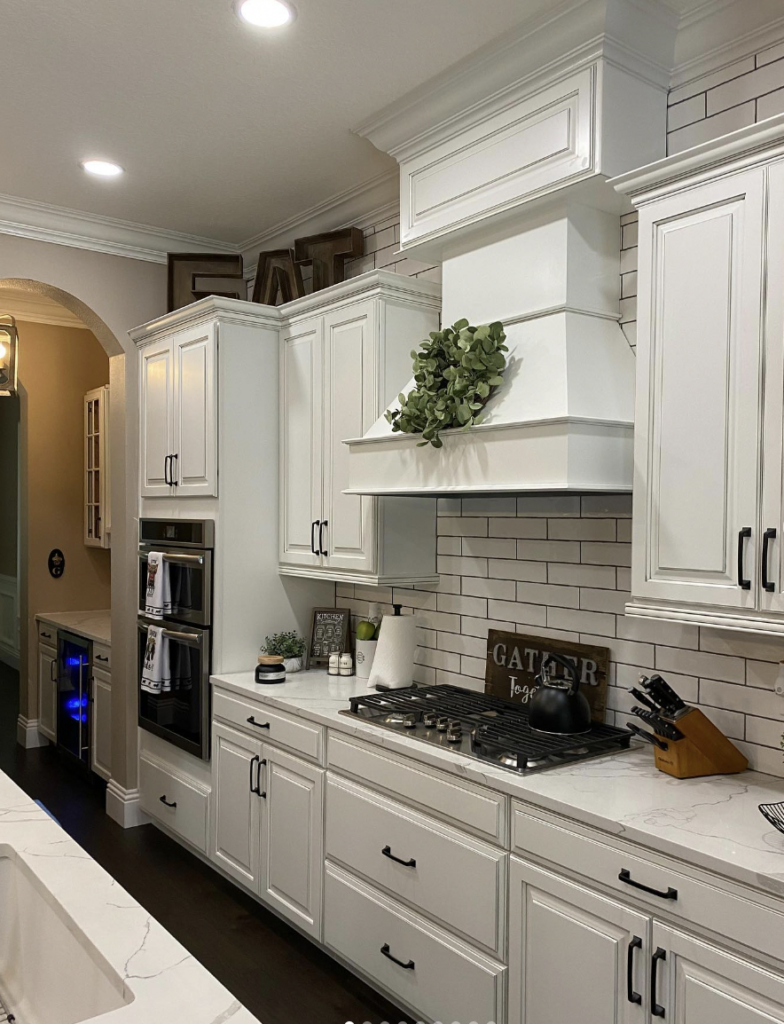 White kitchen cabinets featuring crown molding and black hardware