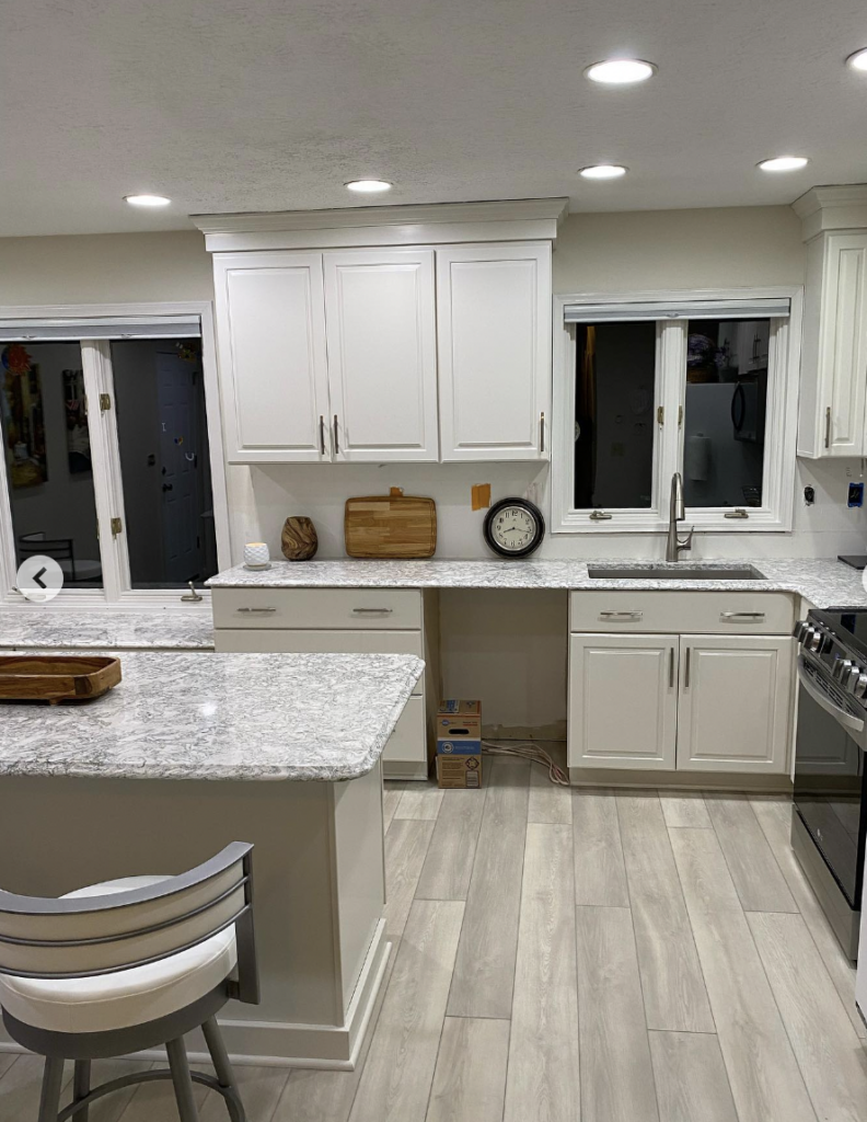 White kitchen cabinets with light wood flooring